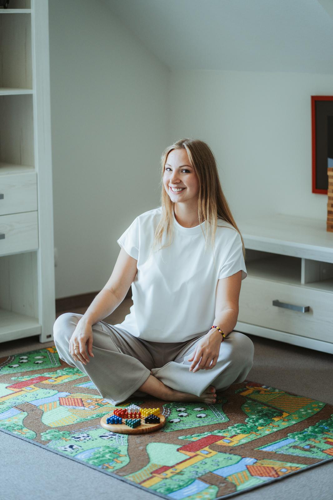 Tatiana Froese sitzt auf einem Spielteppich